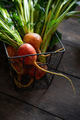 Golden Beets sitting on a wooden table in a wire basket.
