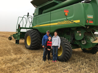 Harvest on the farm. Kent, Kaitlyn and Ty standing in front of our John Deere combine.