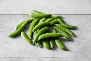 Fresh peas sitting on a wooden table.