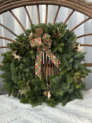 Christmas wreath with a plaid bow on a wooden bench with natural decorative accents.