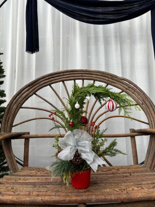 Decorative Christmas arrangement with greenery, ornaments, and a bow on a wooden chair.
