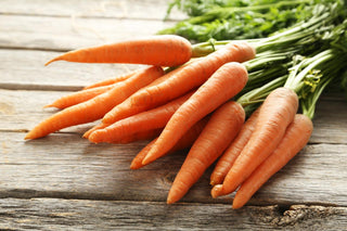 Fresh carrots sitting on a wooden table.